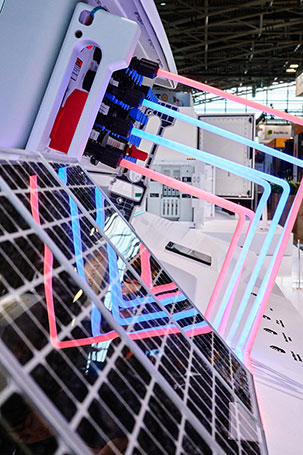 Wechselrichter mit symbolisiserten, leuchtenden Stromleitungen und Modellen von Solarpanelen.