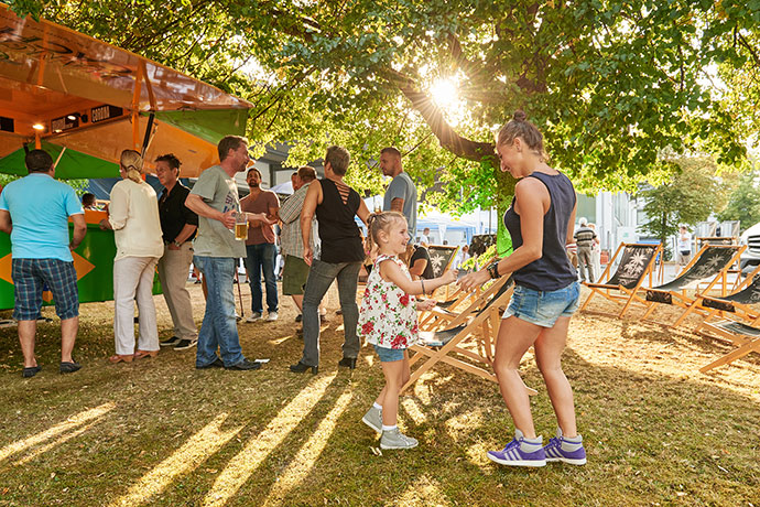 Junge Mutter tanzt mit ihrer Tochter bei einem Firmensommerfest in der untergehenden Sonne, Eventreportage © Florian Freund