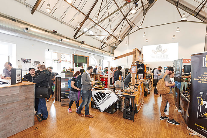 Totale mit vielen Besuchern bei einer Craft-Beer Verkostung in einem alten Industriegebäude, Messefotografie, © Florian Freund