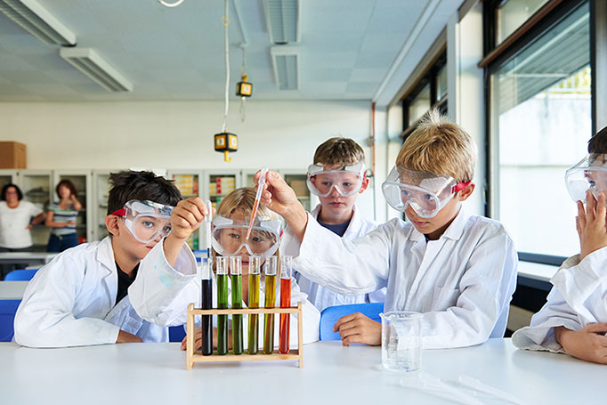 Eine Gruppe Kinder mit Reagenzgläsen beim Experimentieren in der Schule, Peoplefotografie © Florian Freund
